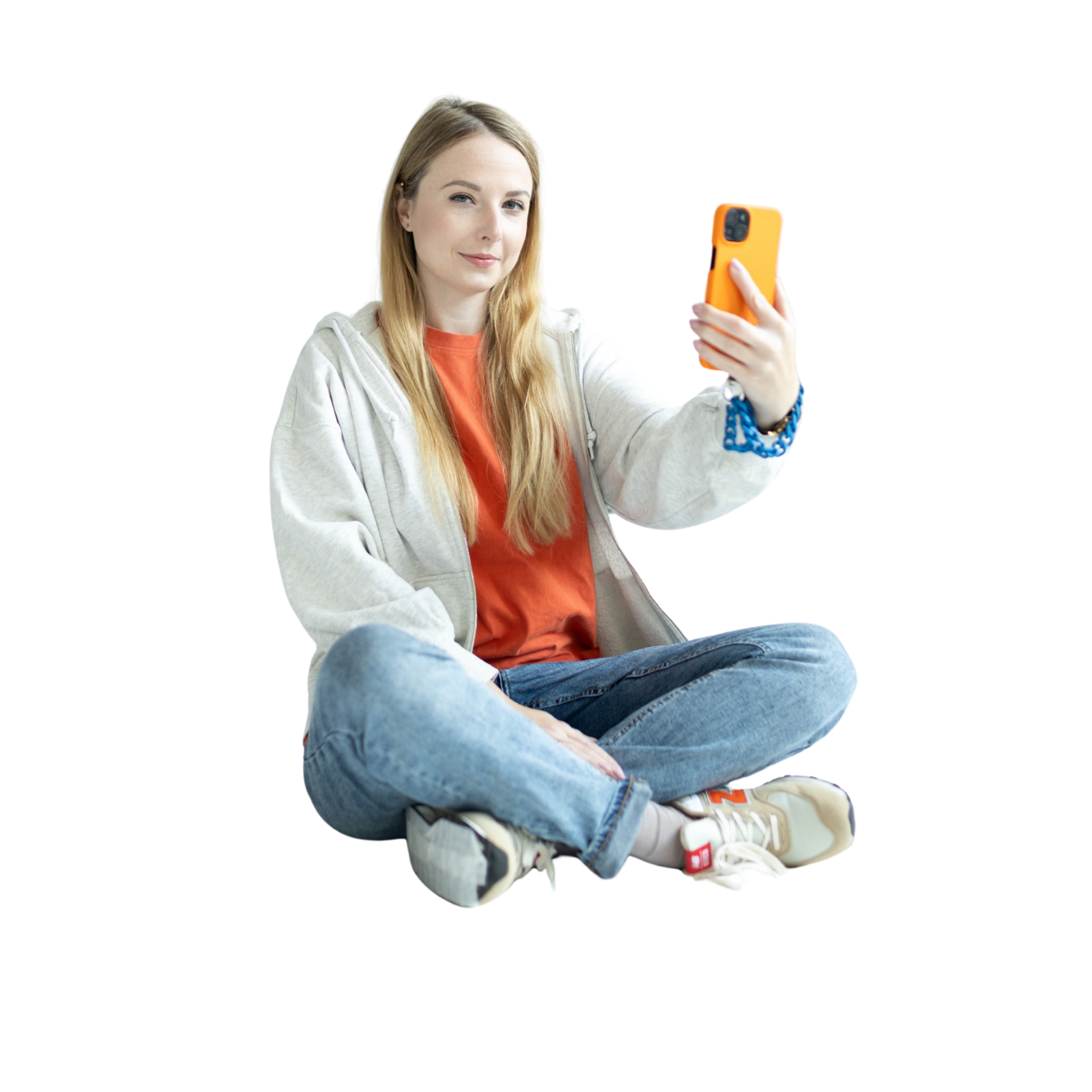 Marta Bagińska Kobieta siedzi na podłodze, trzymając w ręku pomarańczowy telefon.